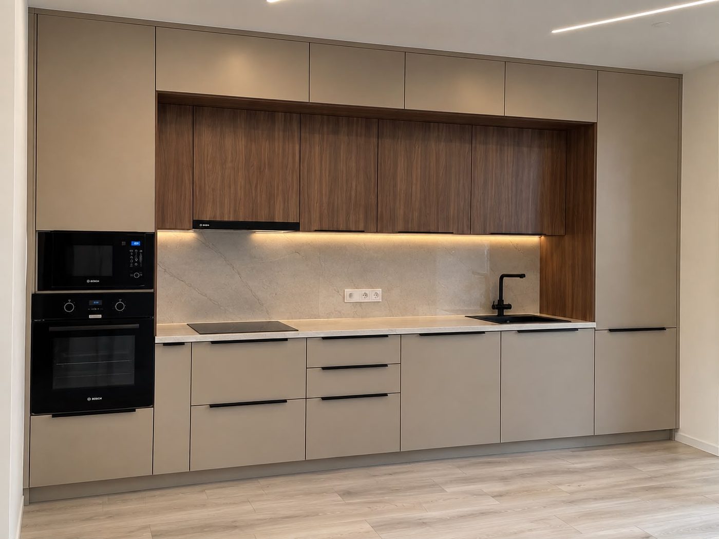 Kitchen with walnut upper cabinets, cream base units, stone backsplash and built-in ovens